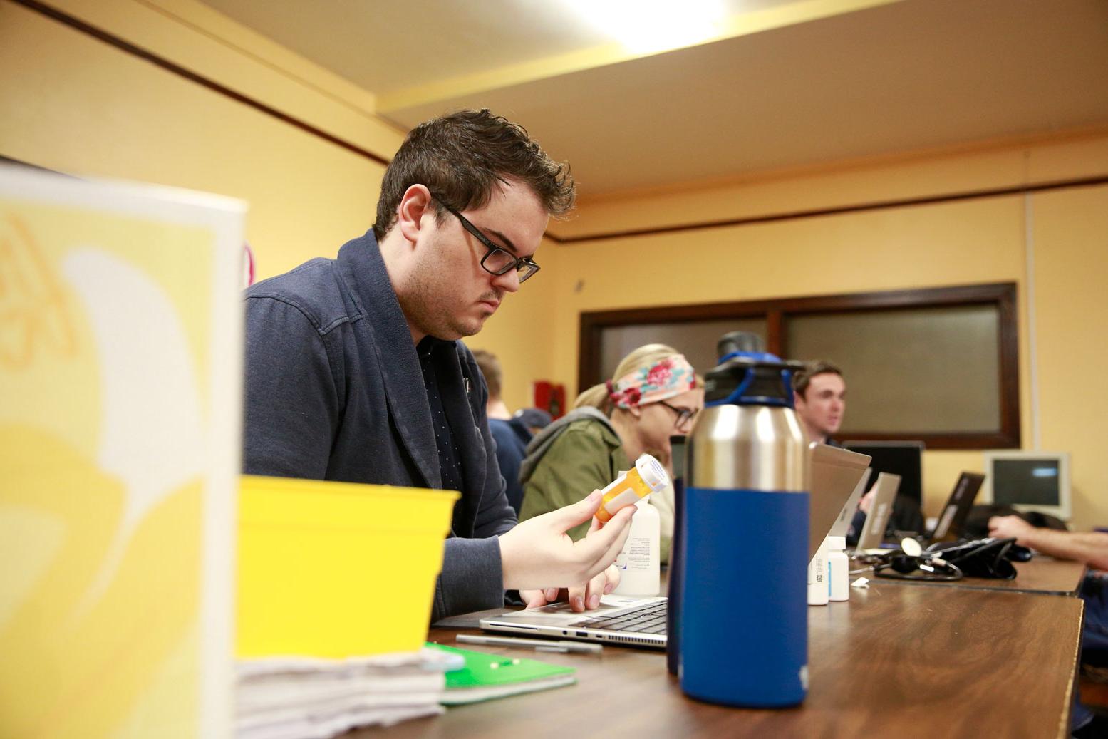 Pharmacy student examines medication container in classroom